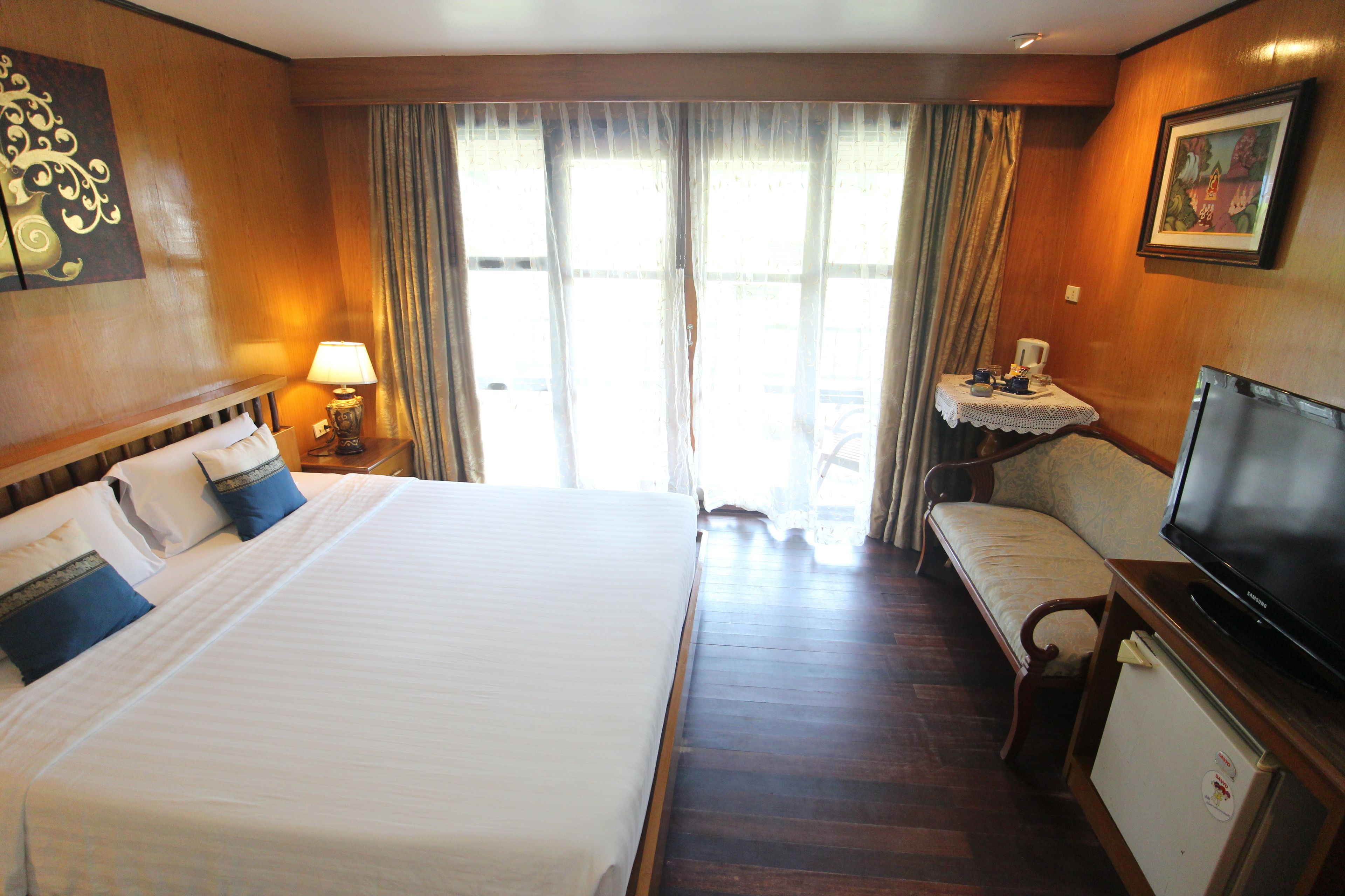 A hotel room with a large bed, a television, a small table, and a sofa.