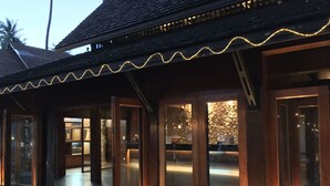 Un bâtiment en bois doté de grandes portes et fenêtres en verre, d’une terrasse en bois et de guirlandes lumineuses.