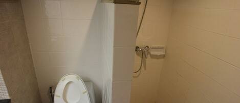 Un baño con inodoro, ducha y pared de azulejos.