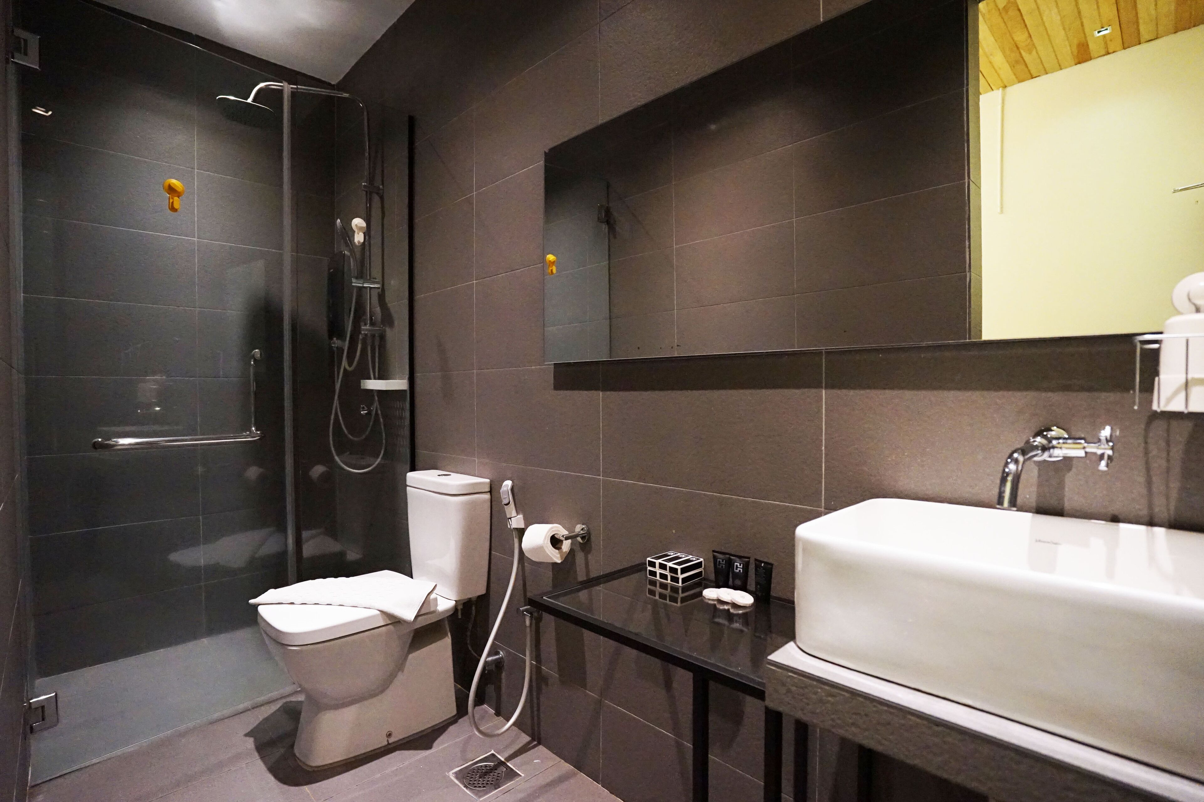 A modern bathroom with a glass shower enclosure, a white toilet, a sink with a mirror above it, and a towel rack.