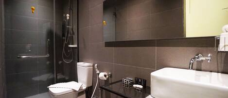 A modern bathroom with a glass shower enclosure, a white toilet, a sink with a mirror above it, and a towel rack.