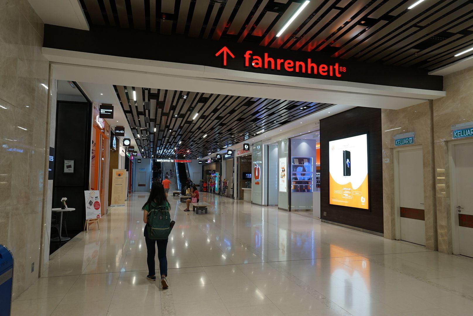 A modern shopping mall corridor with a clear sign for 'fahrenheit88' and a large digital advertisement display.