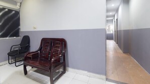 A hallway with a wooden bench, a black office chair, and a wall-mounted clock.