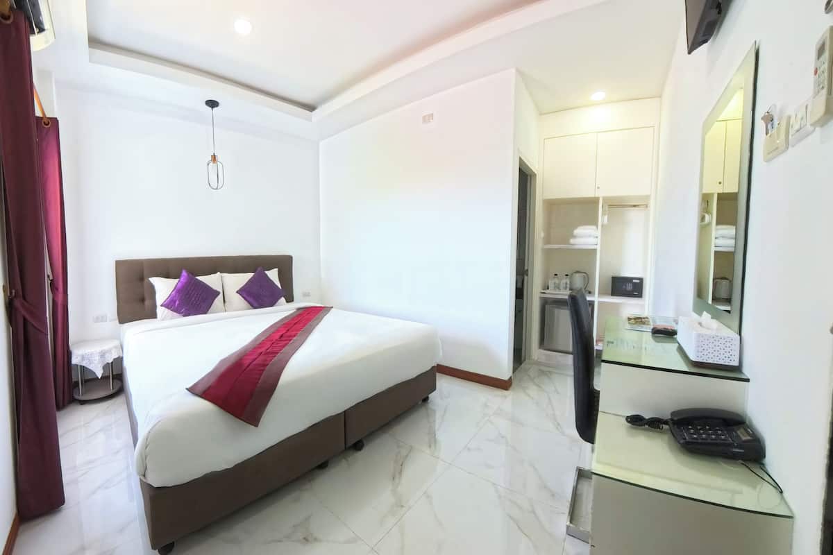 A hotel room with a bed, a desk with a telephone, and a mirror.