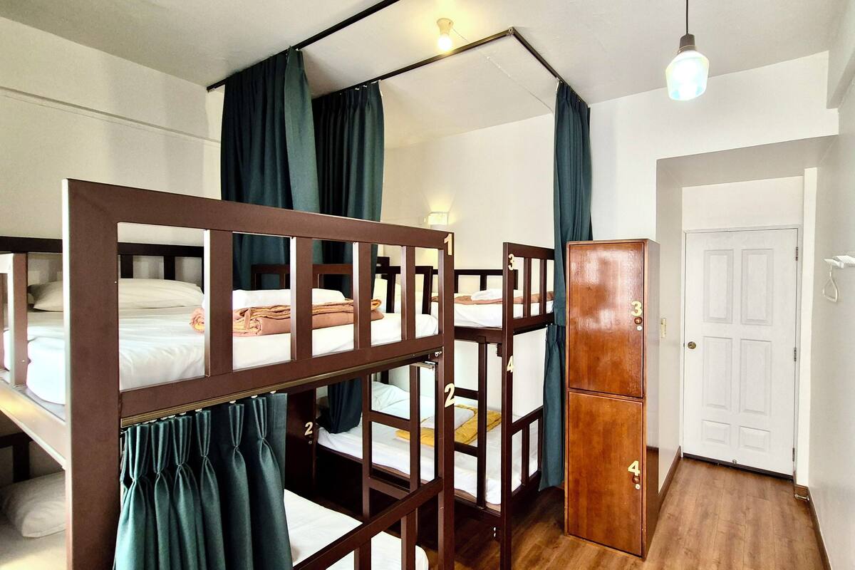 Une chambre avec des lits superposés, une armoire en bois et une porte blanche.