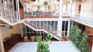 A multi-level atrium with wooden flooring, potted plants, and a staircase.