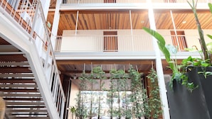 A multi-level interior with wooden beams, white railings, and potted plants.