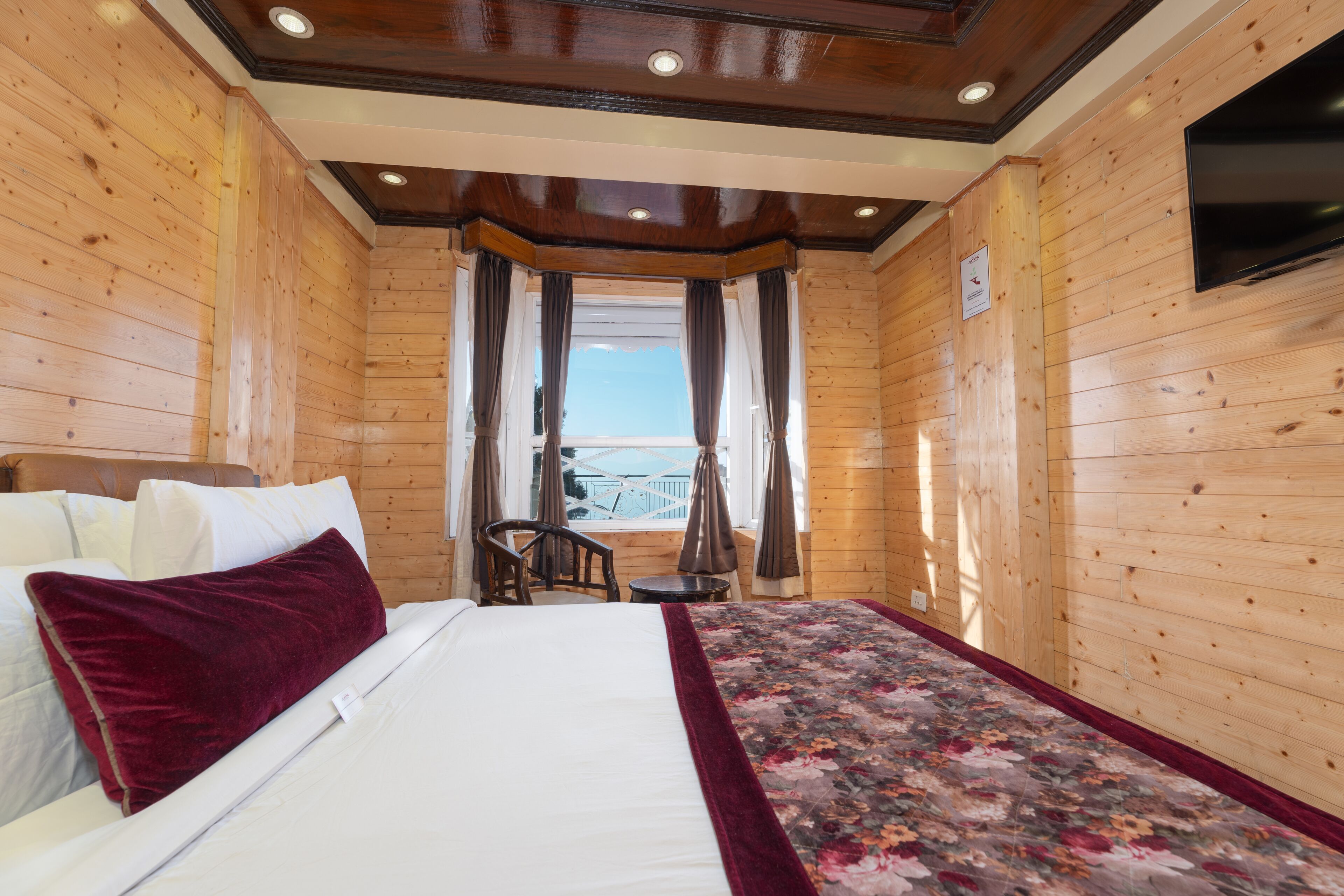 Une pièce de style cabane en bois, comprenant un lit, une chaise, une petite table et un téléviseur fixé au mur.
