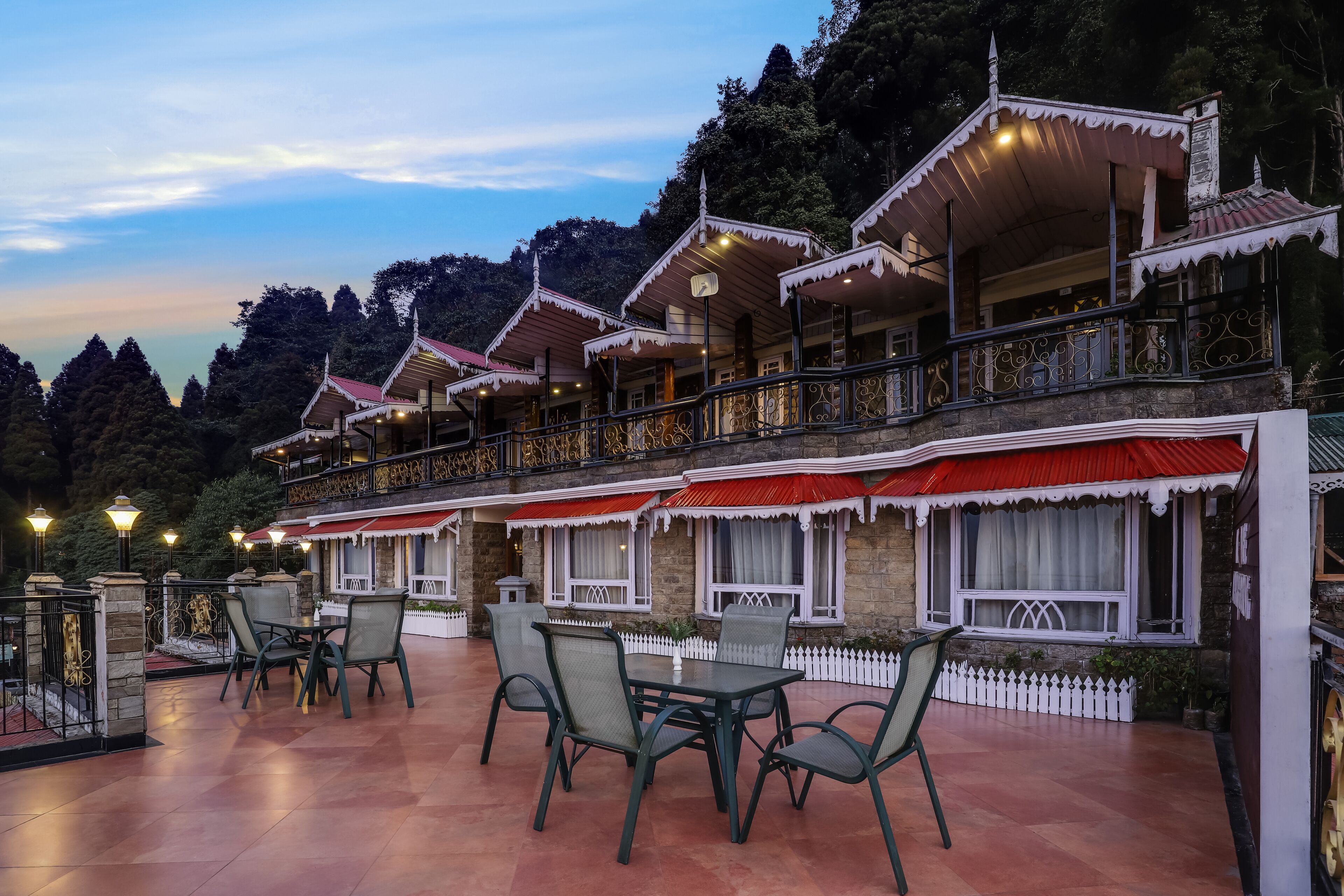 Een gebouw in traditionele stijl, met meerdere balkons en een patio met tafels en stoelen.