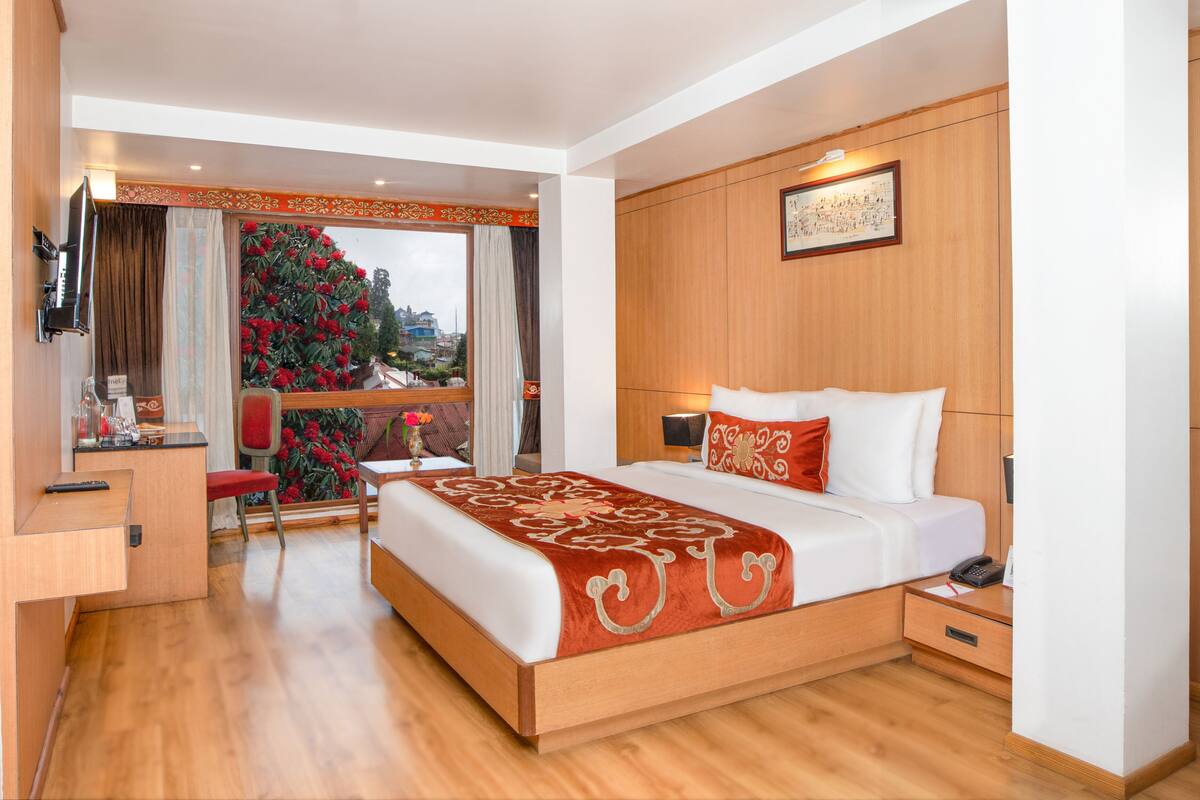 A hotel room with a bed, bedside table, and a desk with a chair.