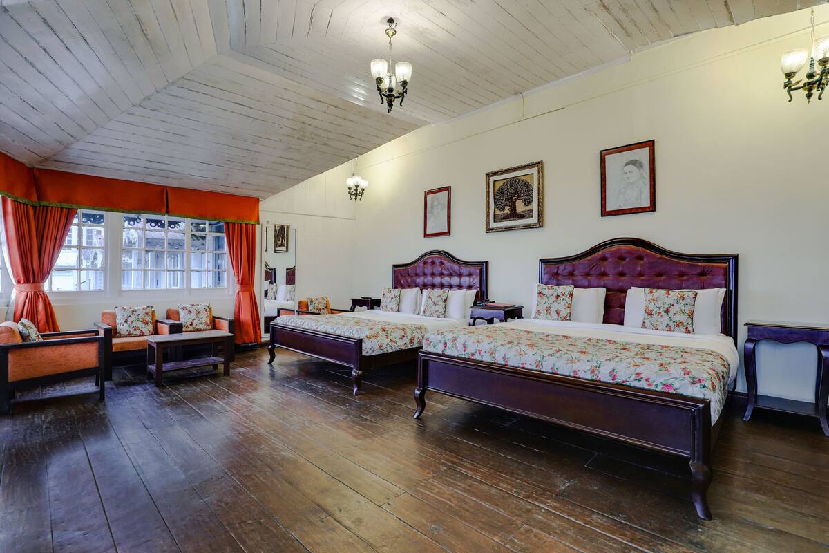 A room with two beds, a sofa, and a chandelier.