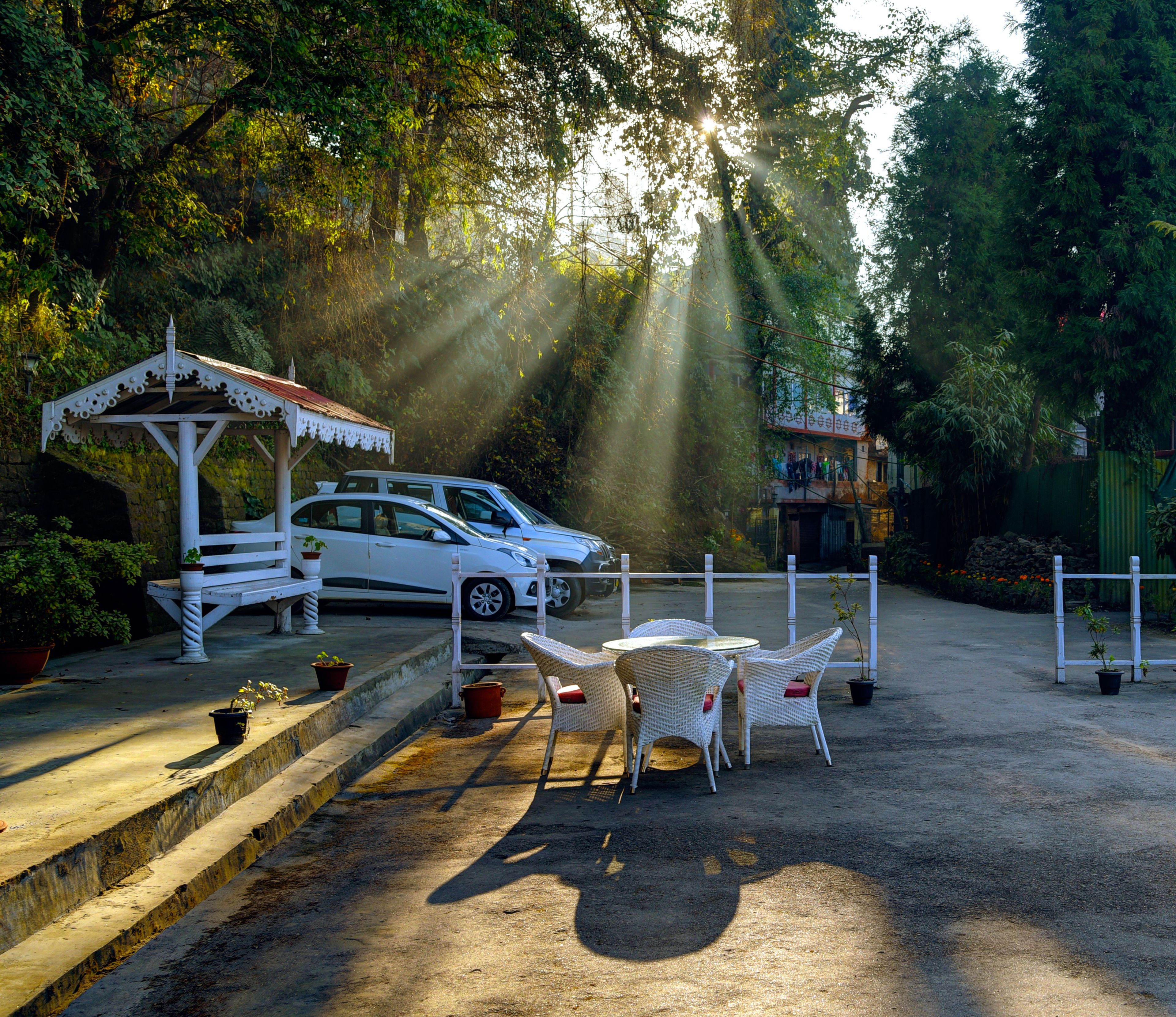 A parking area with white cars, a gazebo, and outdoor seating.