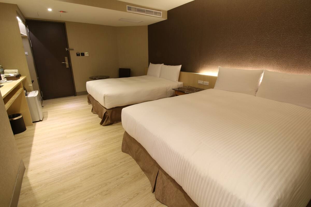 A hotel room with two beds, a desk, and a wardrobe.