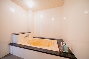 Et moderne badeværelse med en marmorvask, en sort bordplade og en hylde med toiletartikler.