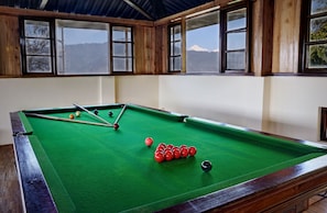 A pool table with balls, wooden walls, and windows with a mountain view. - Summit Namnang Courtyard & Spa (Gangtok)