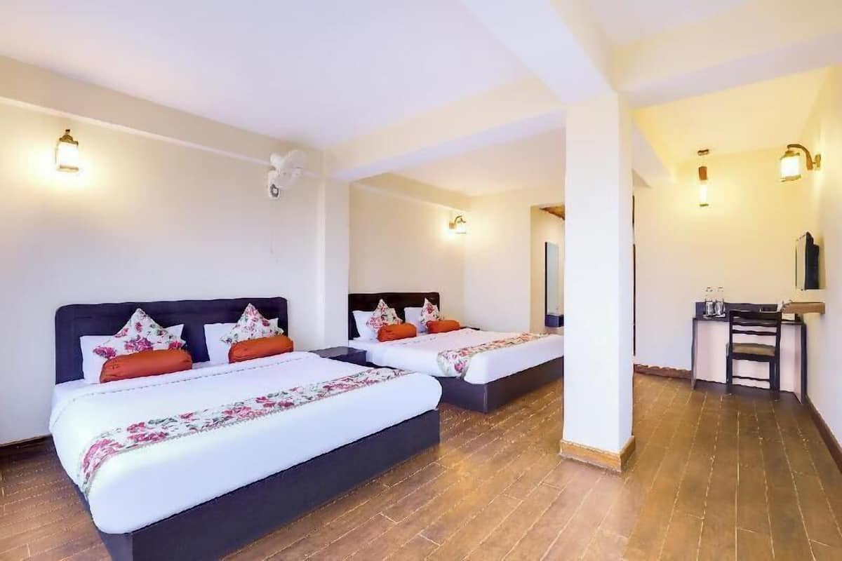 A hotel room with two beds, a small desk, and a mirror.