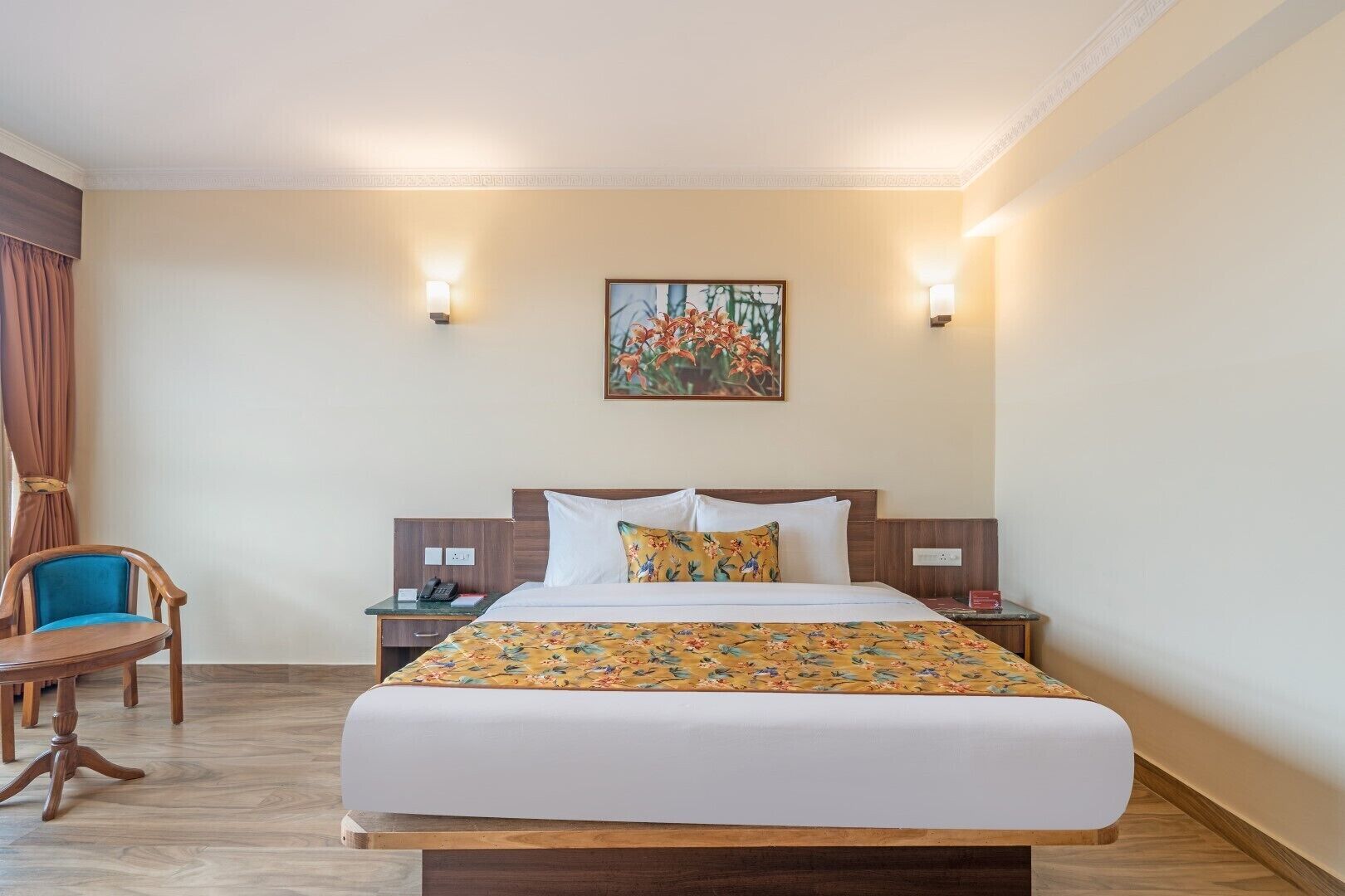 Habitación de hotel con una cama grande, dos mesitas de noche, una silla y un cuadro en la pared.