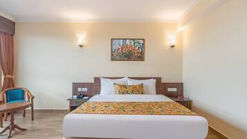 Habitación de hotel con una cama grande, dos mesitas de noche, una silla y un cuadro en la pared.
