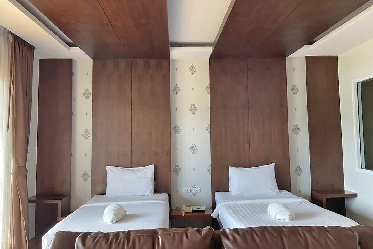 Ein Hotelzimmer mit zwei Betten, Holz-Kopfteilen und Wandpapier mit Muster.