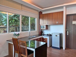 A compact kitchen with a central island, wooden cabinets, a microwave, and a refrigerator.