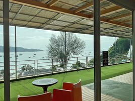 A terrace with a table and chairs, overlooking a body of water with boats.