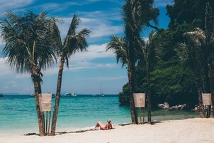 Una playa con palmeras y un mar azul y transparente.
