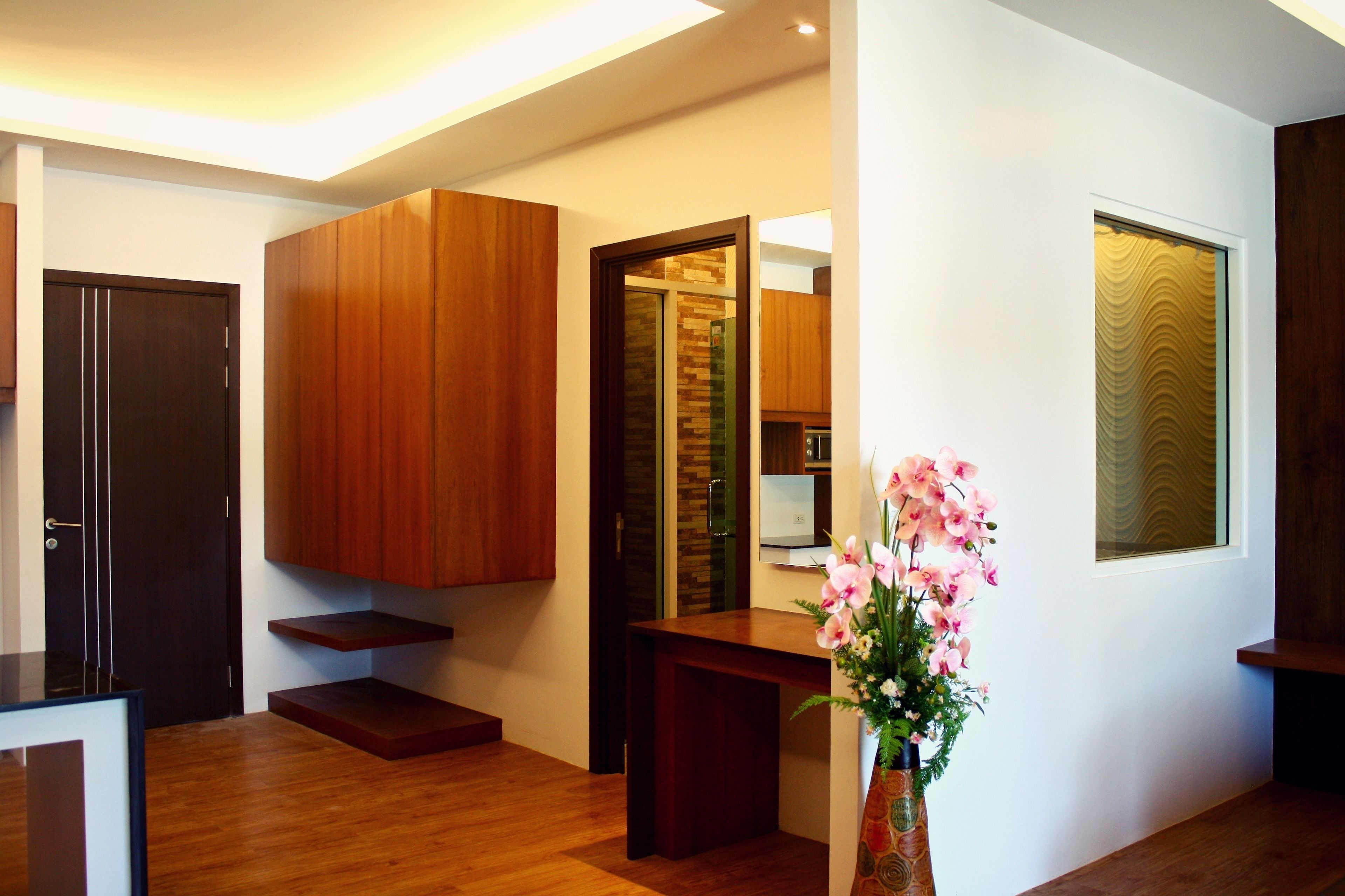 A modern interior with wooden cabinetry, a built-in kitchen, and a vase with flowers.