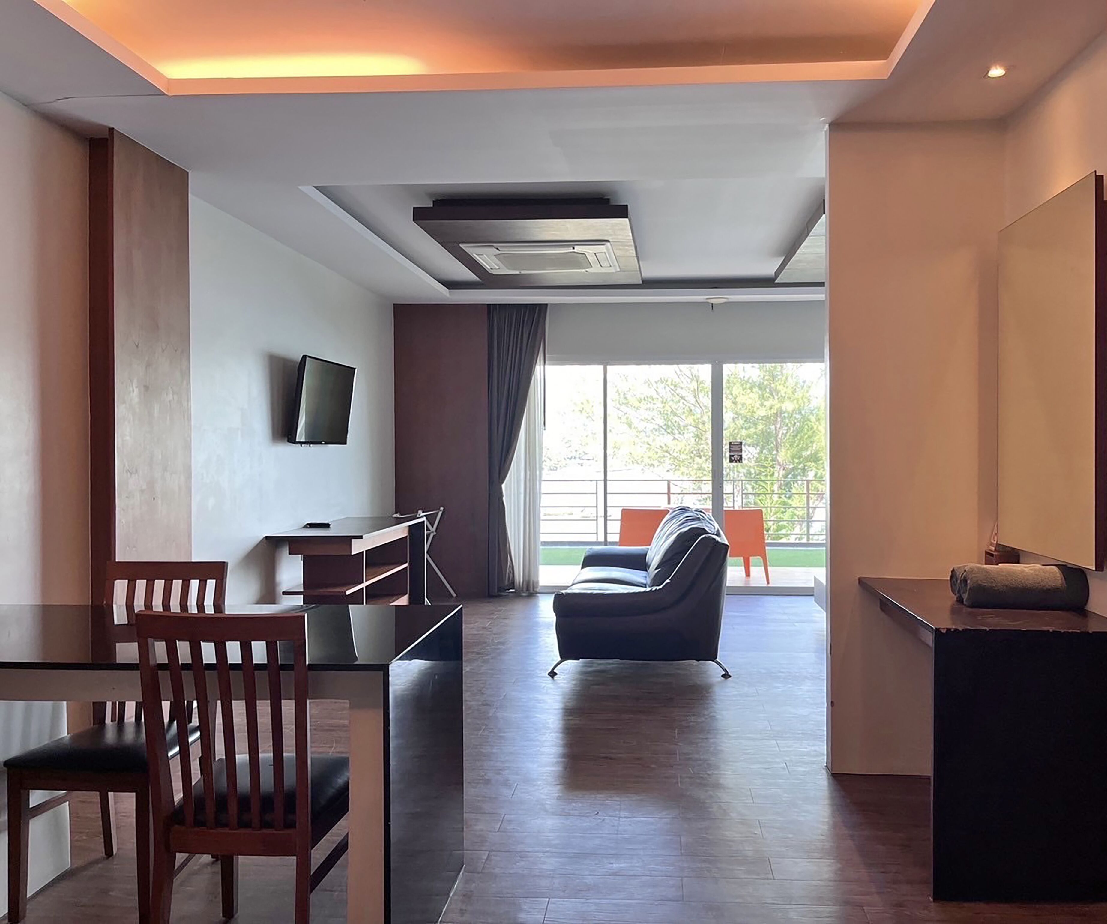 Un salon moderne doté d’un téléviseur à écran plat, de meubles en bois et offrant une vue sur l’extérieur.