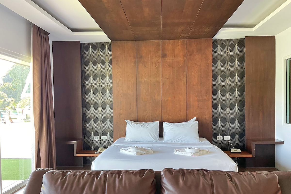 Ein modernes Hotelzimmer mit einem großen Bett, einem braunen Leder-Kopfseitenverkleidung und strukturierter Tapete.