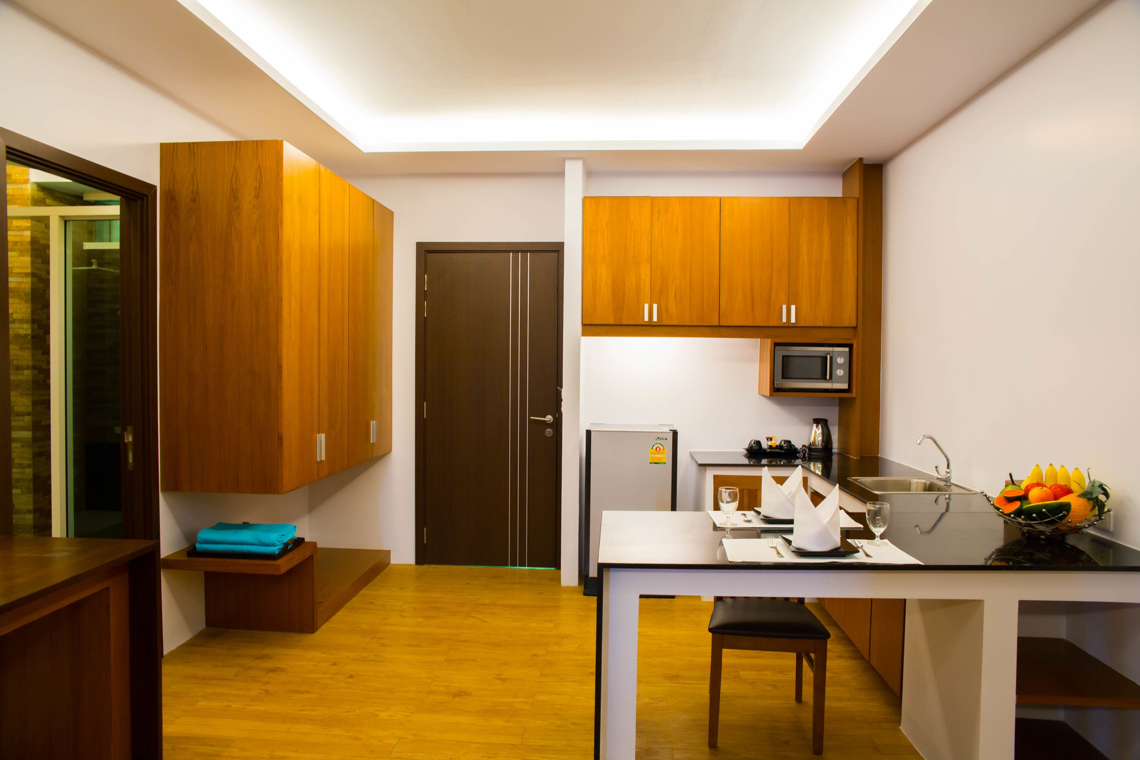 Une cuisine moderne avec des meubles en bois, un réfrigérateur, un four à micro-ondes et un coin repas comprenant une table et des chaises.
