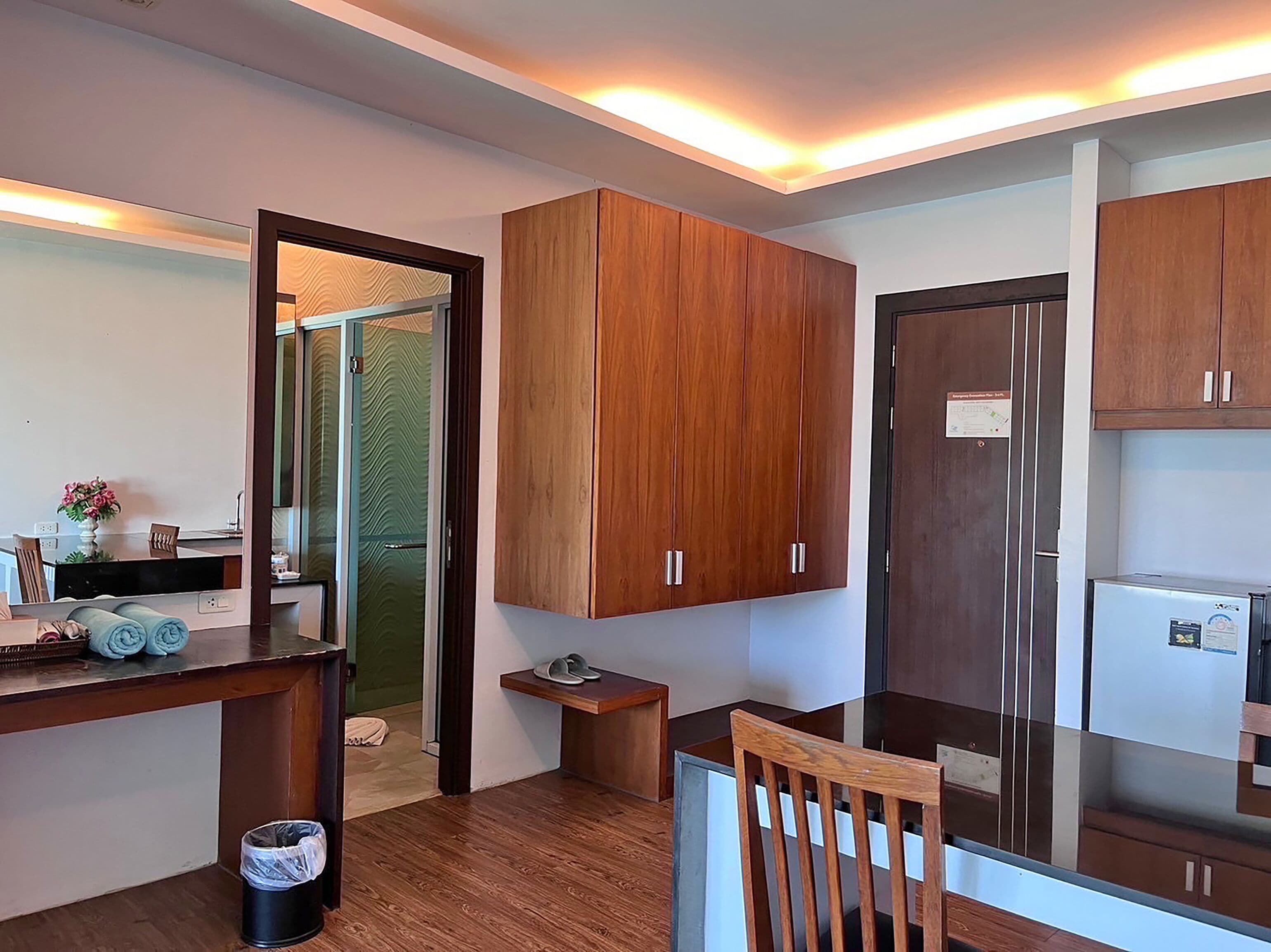 A modern kitchen with wooden cabinets, a refrigerator, and a dining area with a table and chairs.