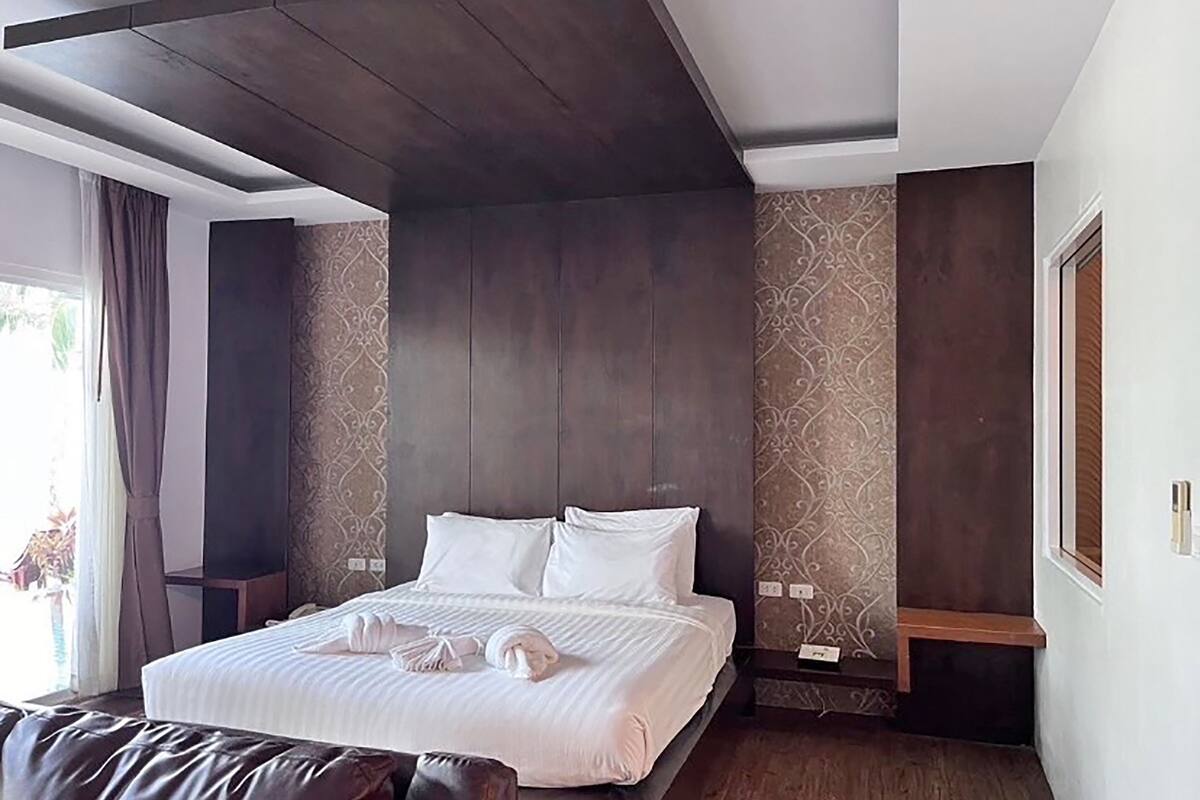 Ein modernes Hotelzimmer mit einem großen Bett, dunklen Holzpaneelen und Wandtapete mit Muster.