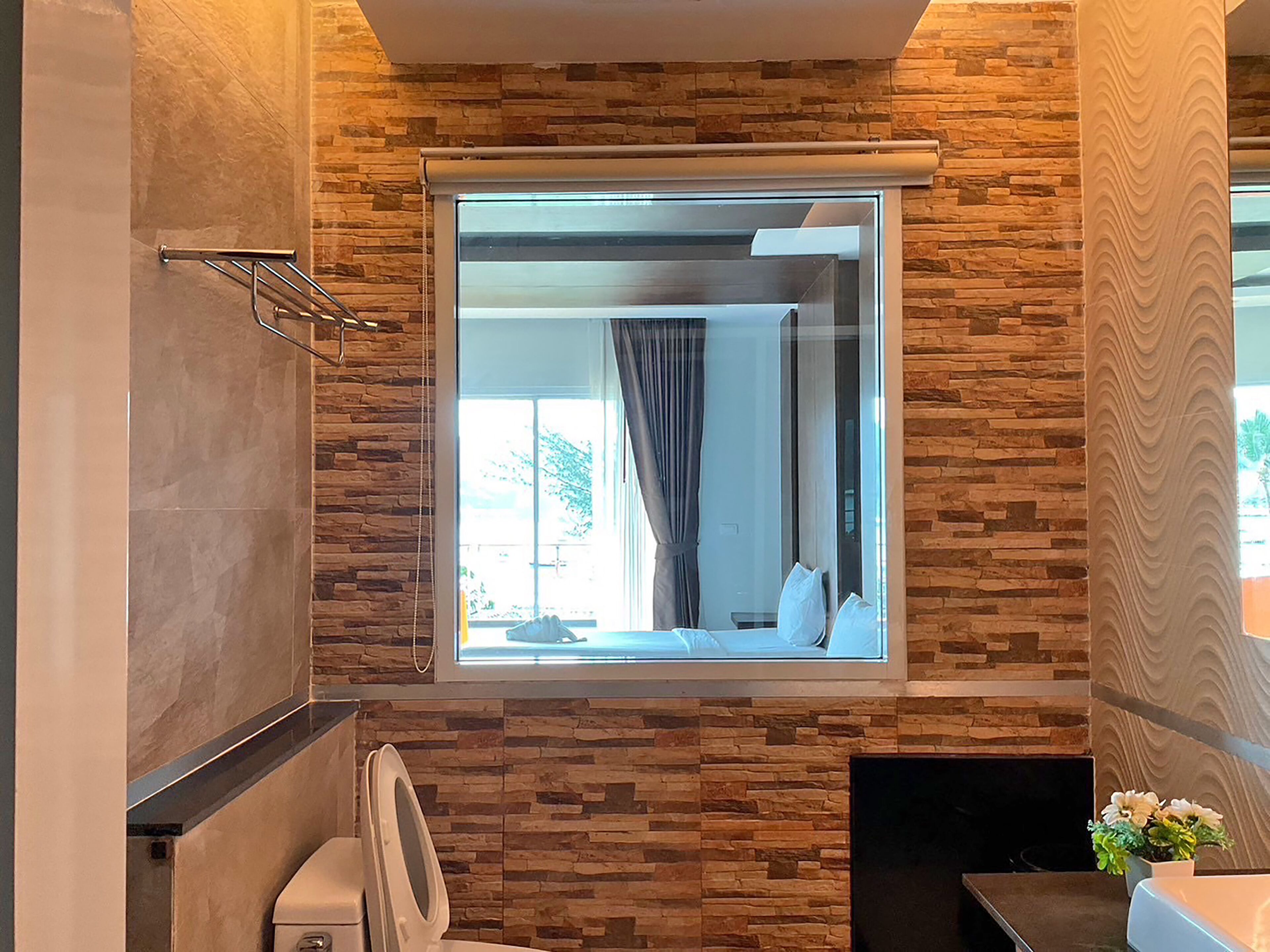 Un baño con pared de piedra, un espejo grande y una ventana.