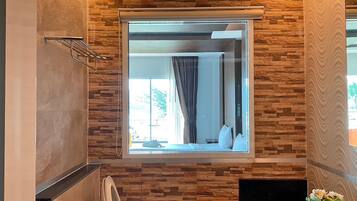 Un baño con pared de piedra, un espejo grande y una ventana.