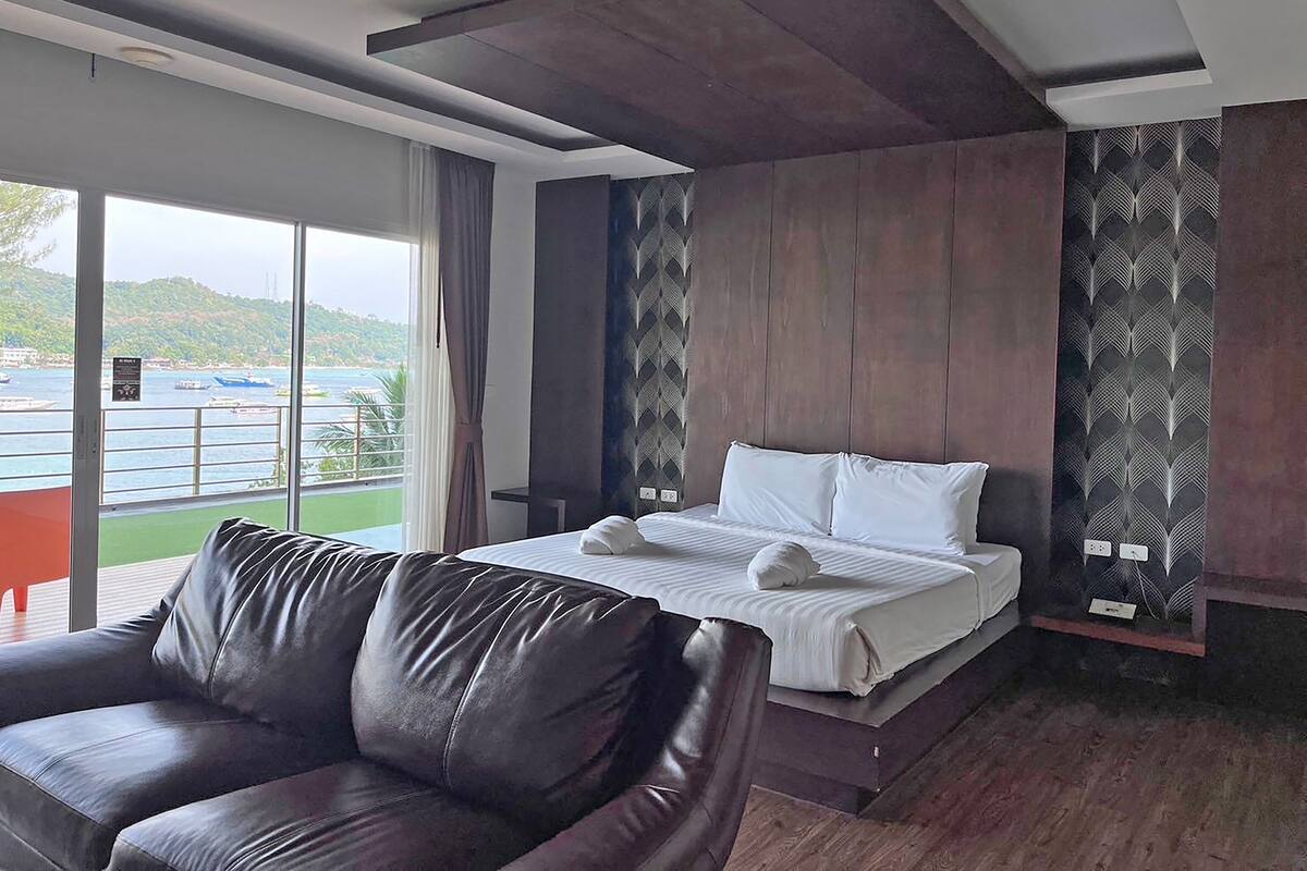 Ein modernes Hotelzimmer mit einem großen Bett, einer Ledersofa und Blick aufs Meer.