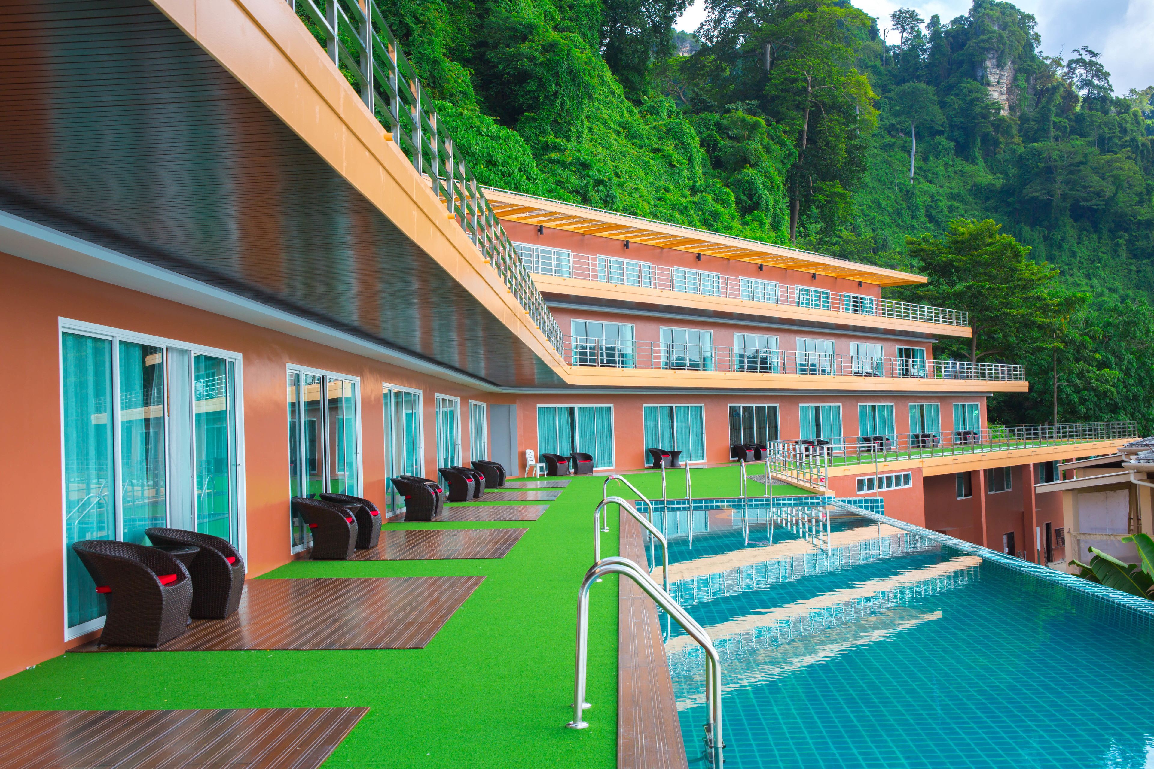 A poolside area with a pool, lounge chairs, and a building with multiple windows and balconies.