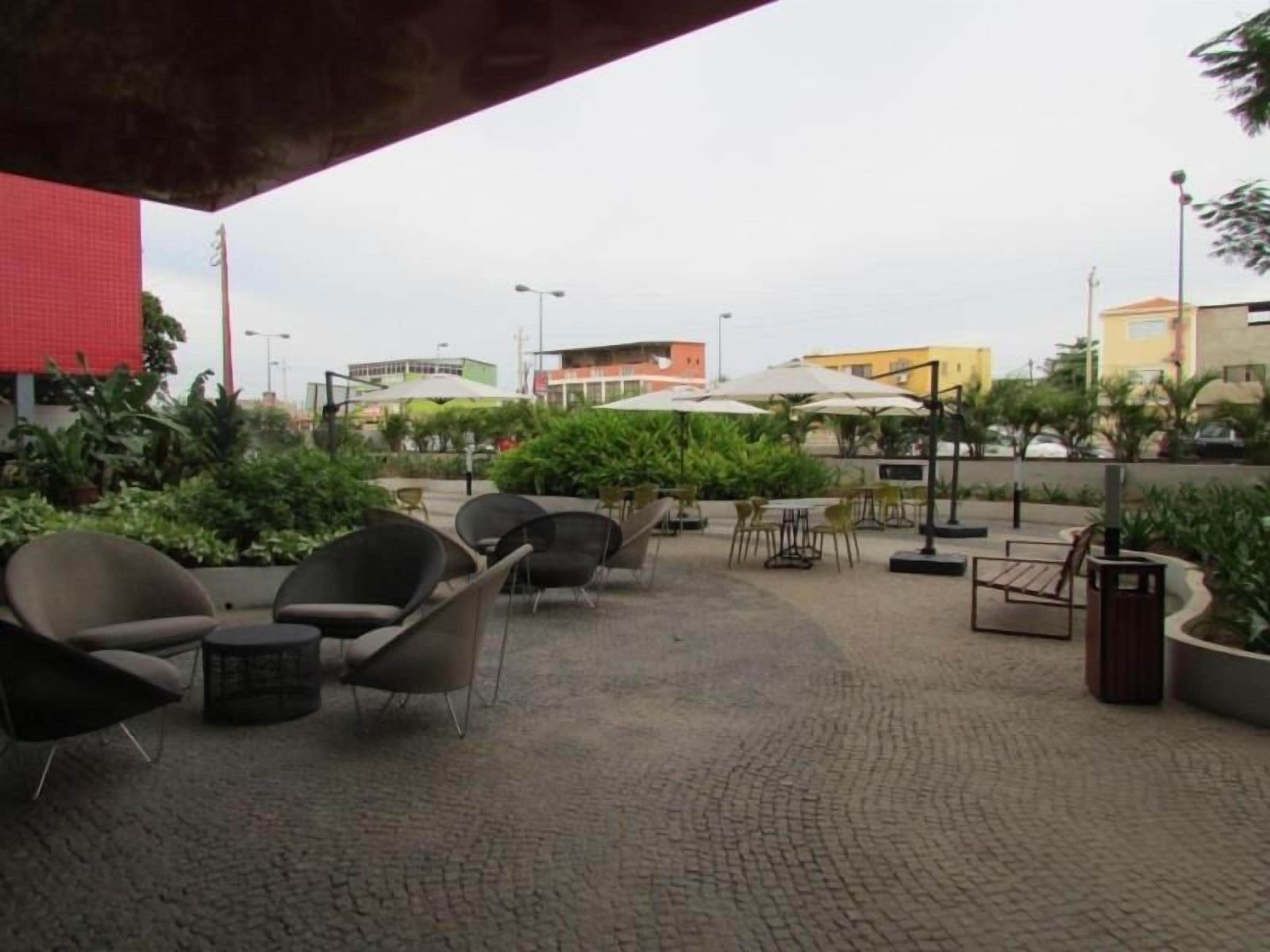 An outdoor patio area with seating arrangements, tables, and umbrellas.