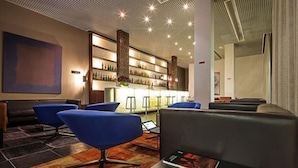 A modern lobby with blue chairs, a bar area, and a fireplace.