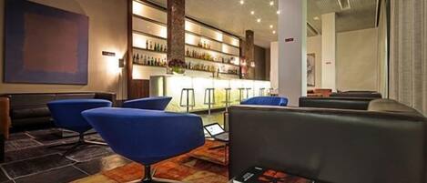 A modern lobby with blue chairs, a bar area, and a fireplace.