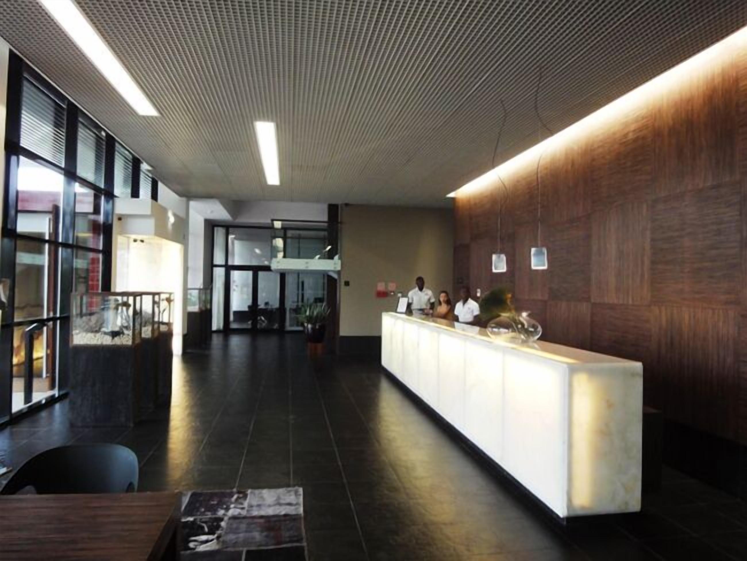 Una zona de recepción moderna con un mostrador de madera, un panel de vidrio y un suelo de baldosas.