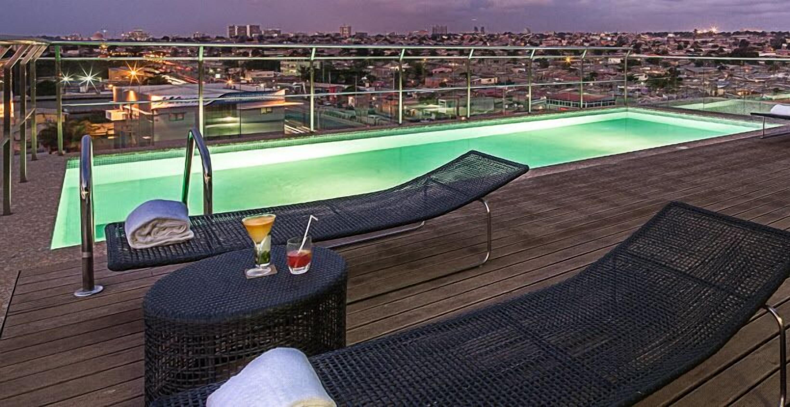 A rooftop pool area with lounge chairs and a bar.