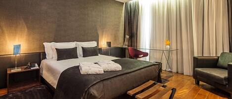 Una habitación de hotel moderna con una cama grande, un escritorio, una silla y un sofá.