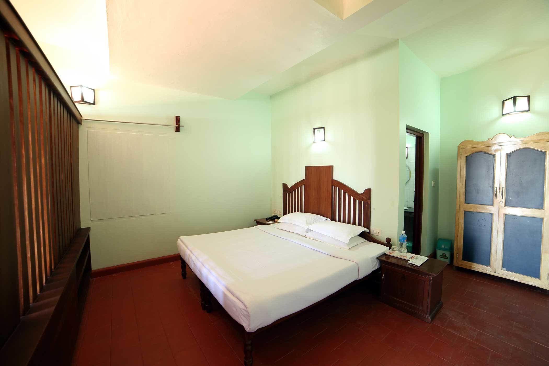 Un dormitorio con una cama de madera, una mesita de noche, un armario y suelo de baldosas.