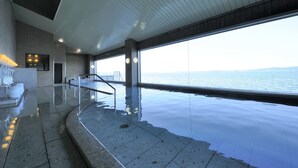 Una piscina infinita con vistas al mar, una escalera y un área de descanso de diseño moderno.