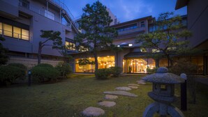 Un edificio con jardín japonés tradicional, farol de piedra y entrada bien iluminada.