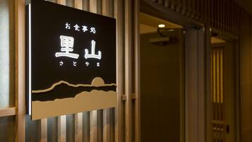 A sign with Japanese characters and a landscape design, mounted on a wall with vertical wooden slats.
