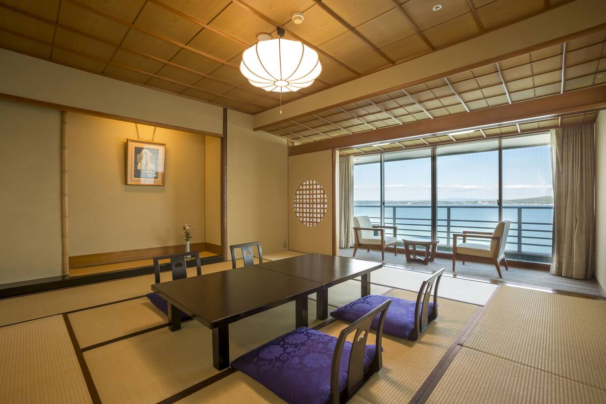 A traditional Japanese room with tatami flooring, a low table, and seating.