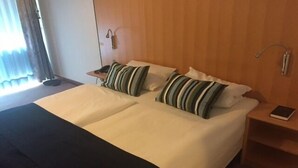 Un lit double avec des oreillers à rayures, une table de chevet avec un livre et une petite table de nuit avec une lampe.