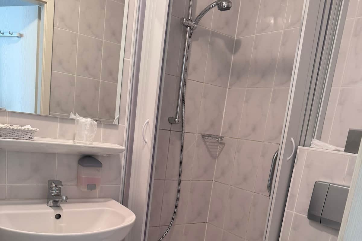 A bathroom with a shower, toilet, sink, and a mirror.