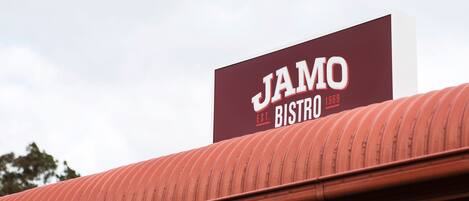 Schild für Jamo Bistro mit rotem Dach und blauem Himmel im Hintergrund.
